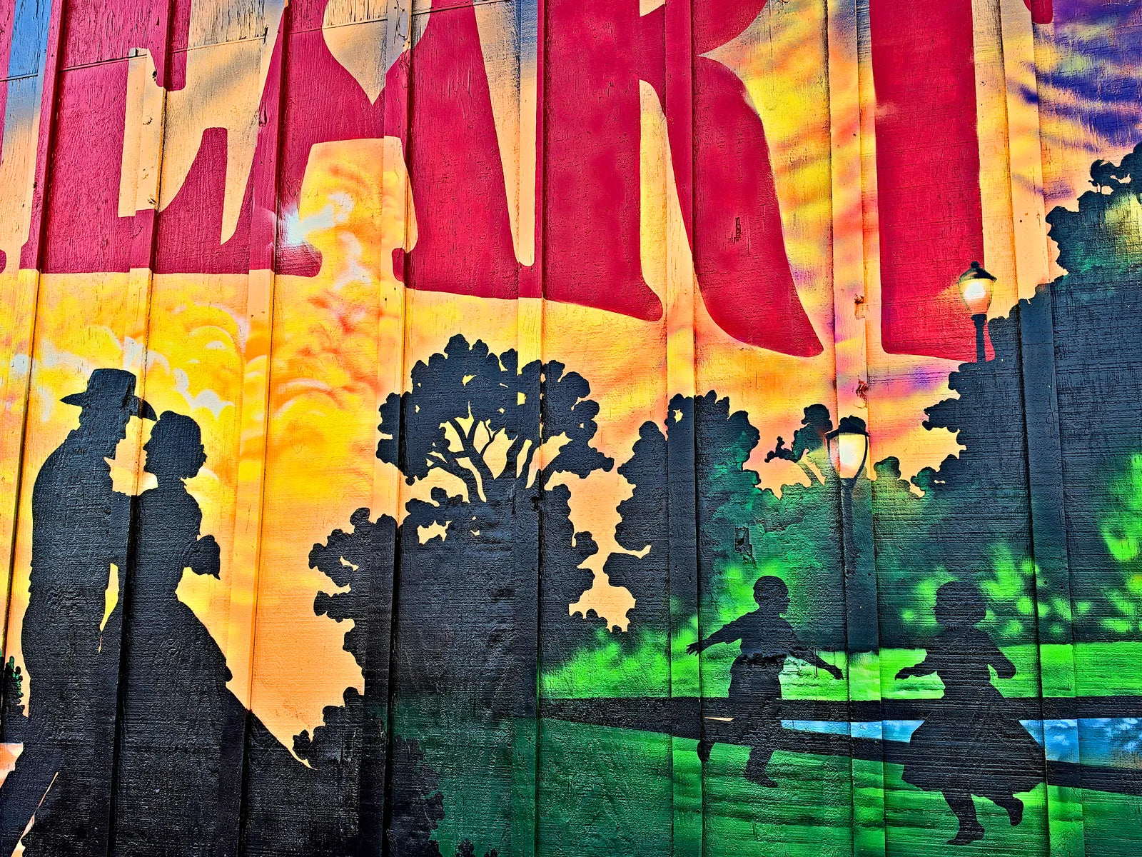 Silhouettes of kids racing across a sunlit park beneath the red HEART lettering