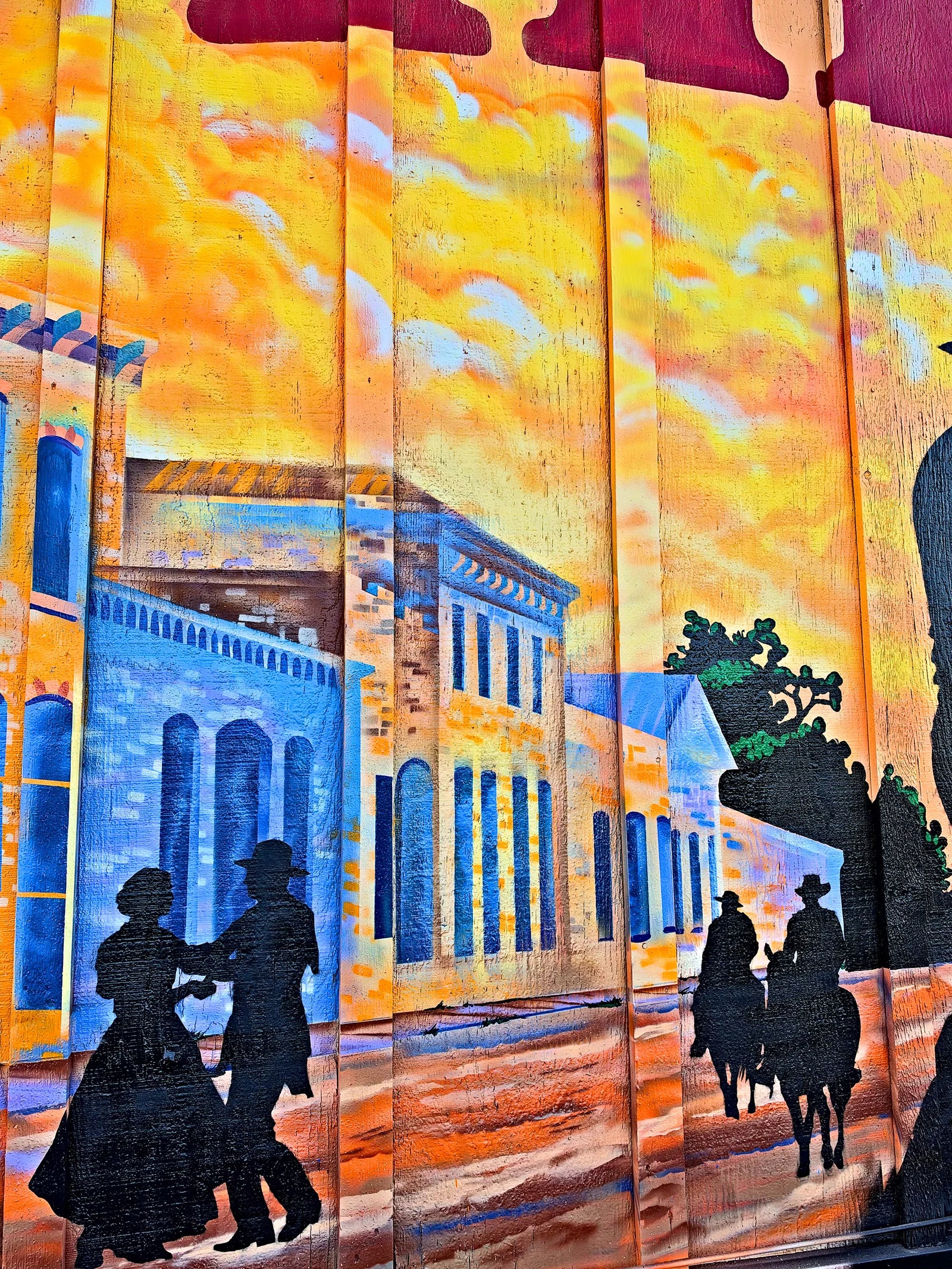 A dancing couple and riders on horseback in front of a historic blue downtown building